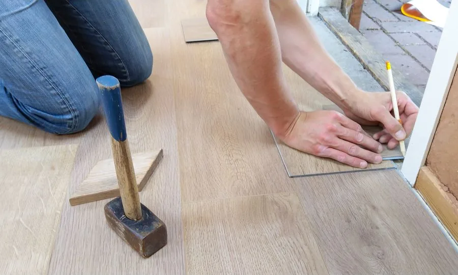 Worker measuring and fitting a replacement floor board
